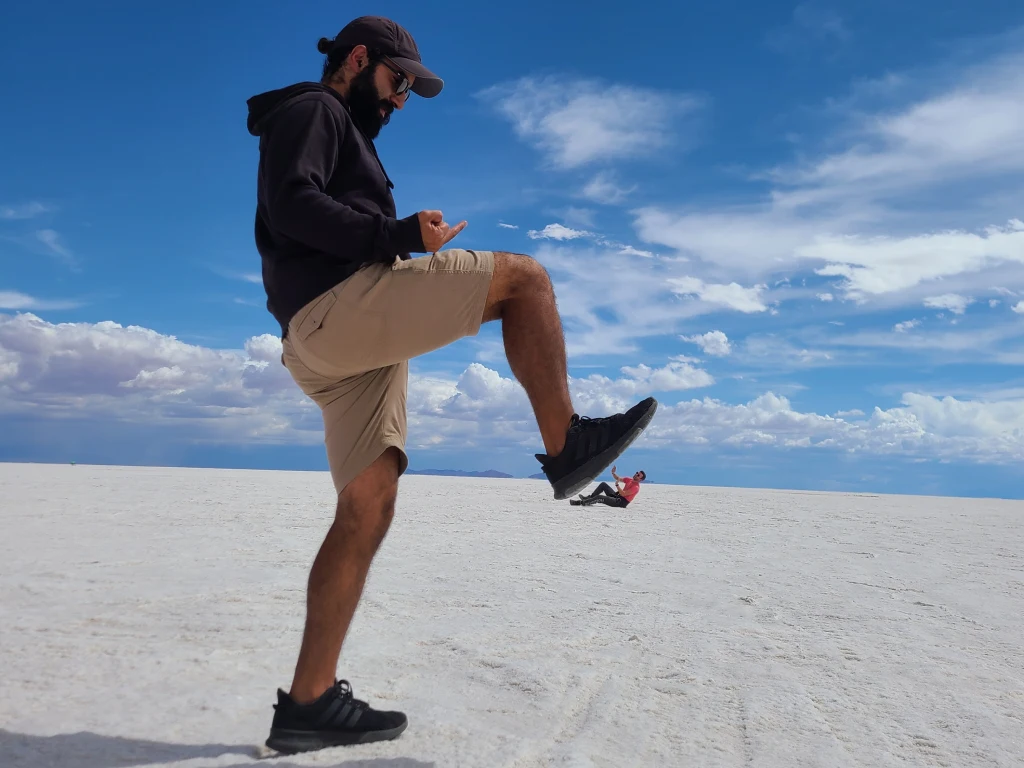 Man pretends to stamp on man in distance on salt flat bolivia tour