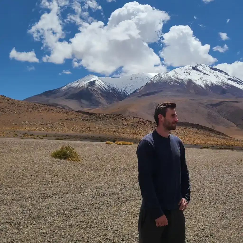 man looks into distance with mountains in background in bolivia
