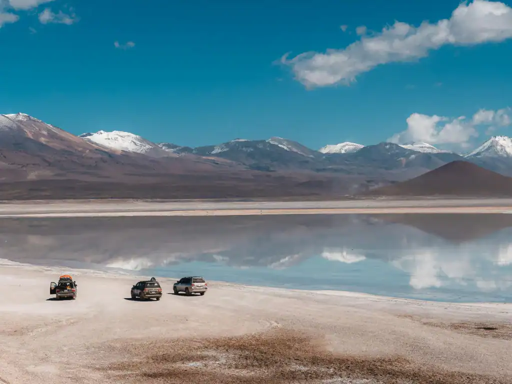 4x4 vehicles on the salt flats of Bolivia’s Altiplano with mountains reflected in the water