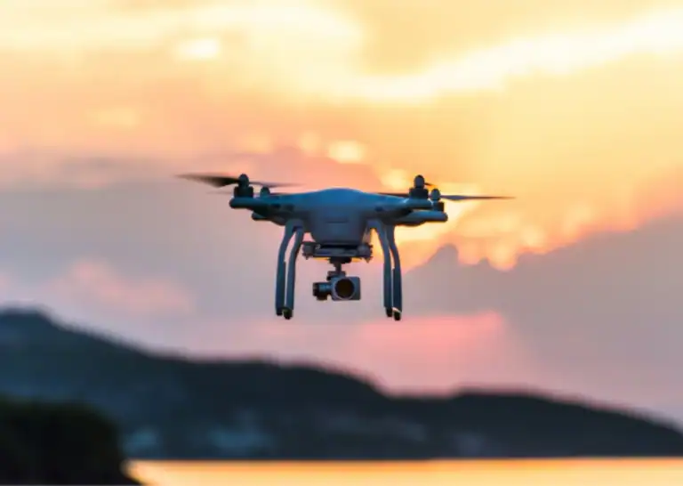 White drone hovering at sunset with mountains in background