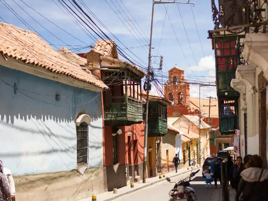 Narrow street lined with colourful buildings in Bolivia, commonly used by pedestrians and local minibuses for everyday transport.