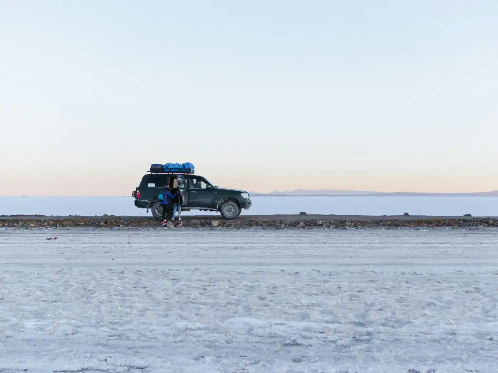 4x4 vehicle crossing Bolivia’s Uyuni Salt Flats during a group tour adventure.