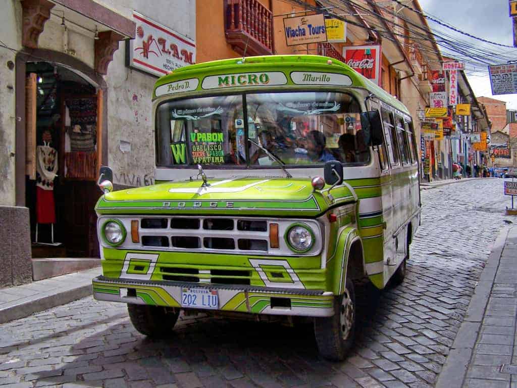 Local micro bus driving through a street in Bolivia with Spanish transport signs