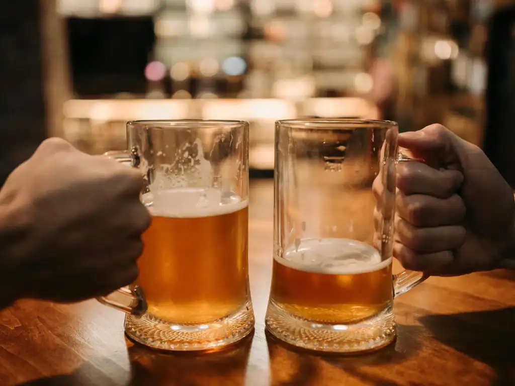Two people drinking beer inside a warm bar setting during a night out in Bolivia.