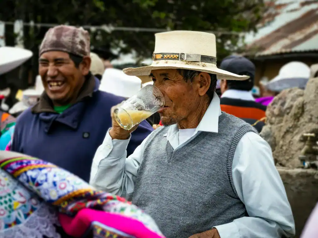 Local man drinking a traditional beverage during a social gathering in rural Bolivia