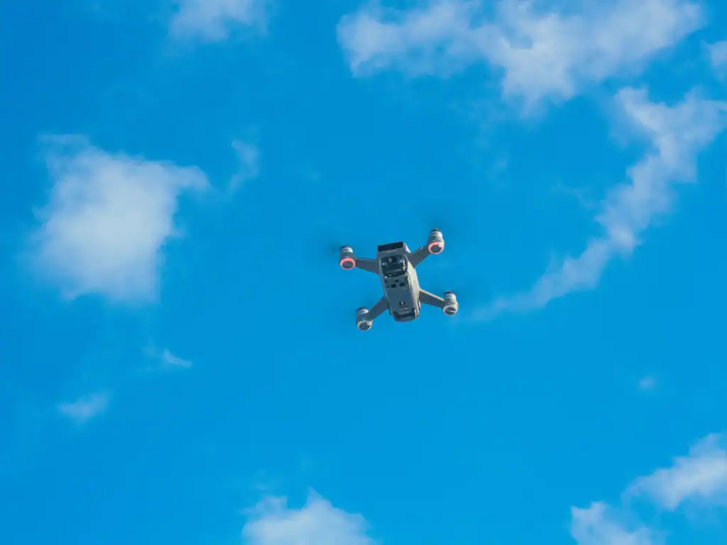 Recreational drone flying against a clear blue sky above an urban environment.