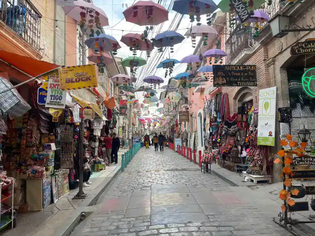 Colourful market street in La Paz with hanging umbrellas, souvenir shops and traditional Bolivian crafts.