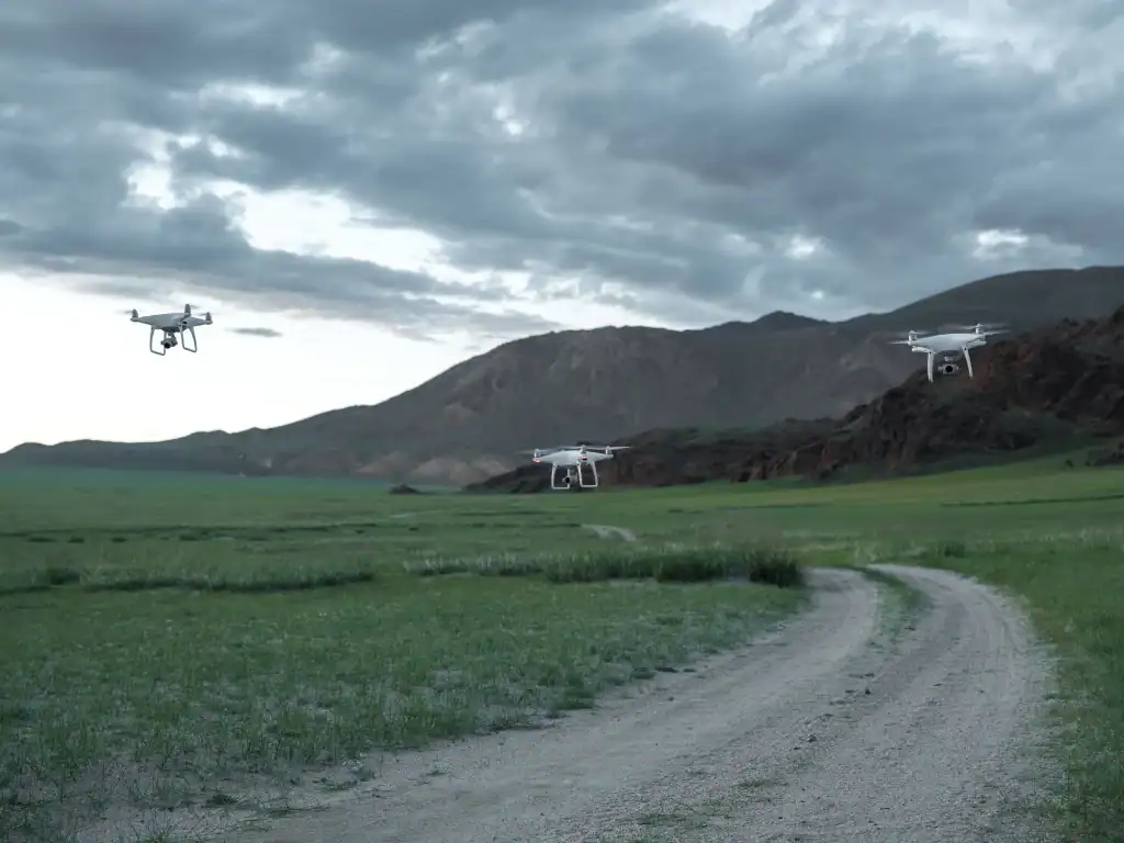 Multiple drones flying over a remote landscape away from urban areas and crowds.