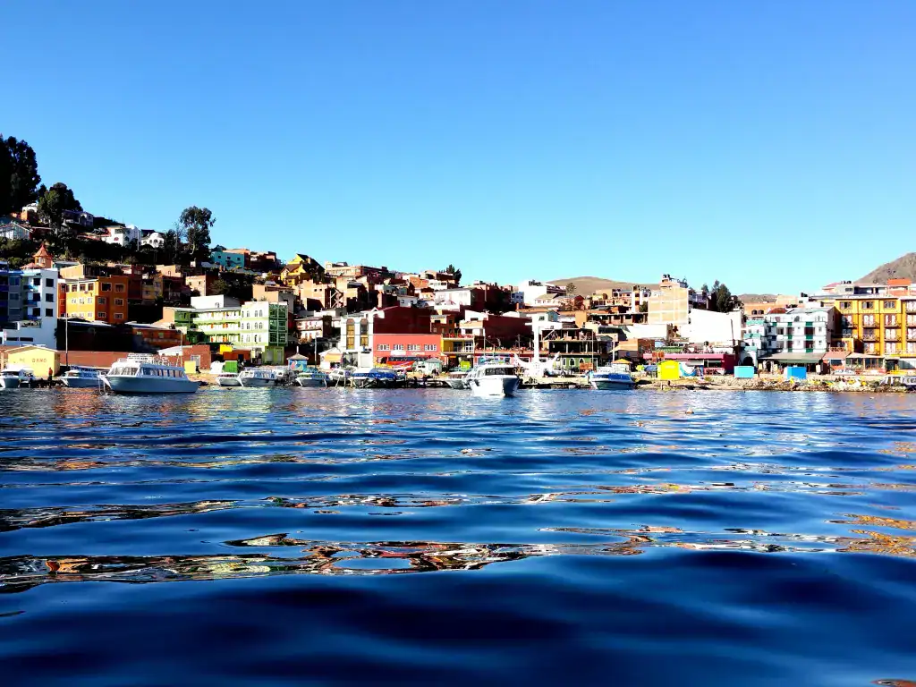 Vibrant waterfront of Copacabana with colourful buildings, boats and mountain scenery.