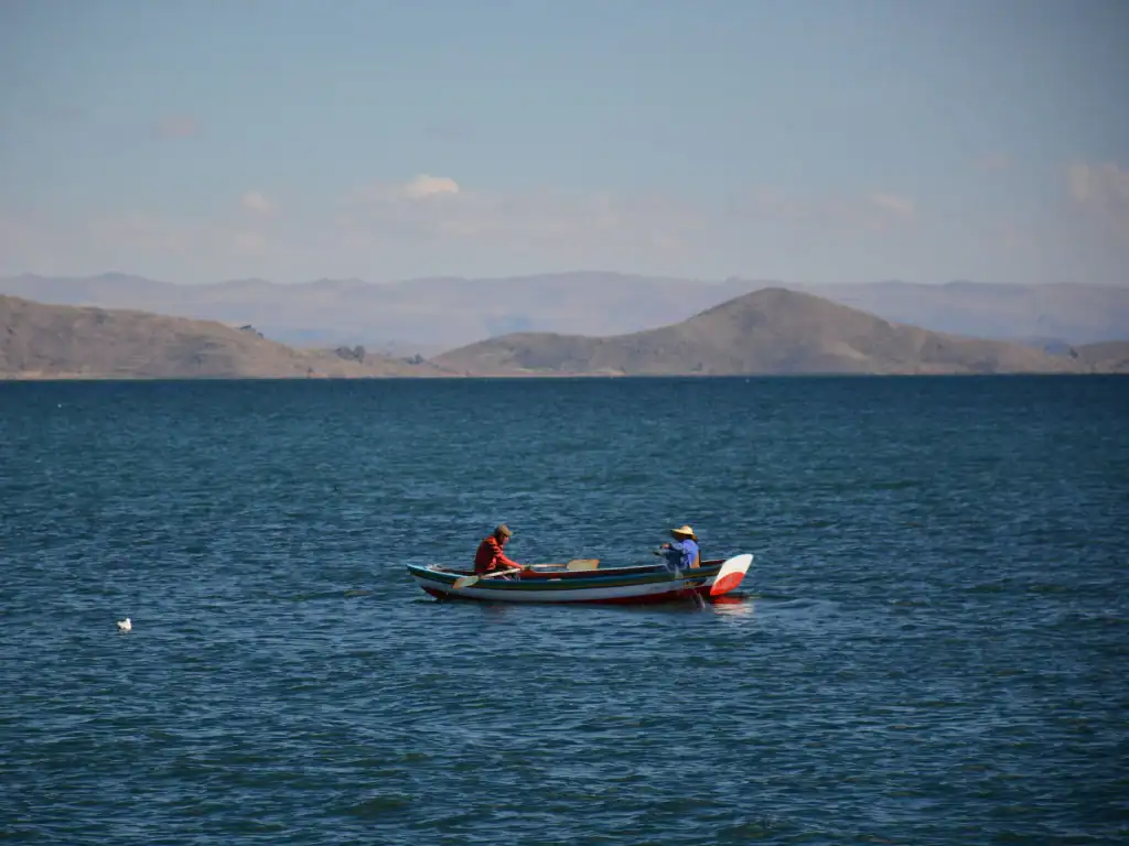 Local fishermen rowing a small boat across the calm waters of the high-altitude lake.